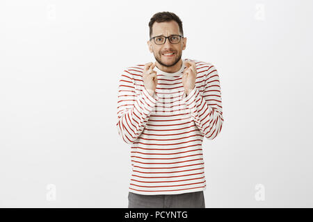 Si prega di boss ho bisogno di questa possibilità. Preoccupati e ansiosi bello maschio con setola nel quartiere alla moda di occhiali neri, sollevando le dita incrociate e mordere il labbro mentre io Foto Stock