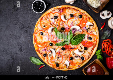 Pizza vegetariana con funghi e olive su sfondo nero. Foto Stock