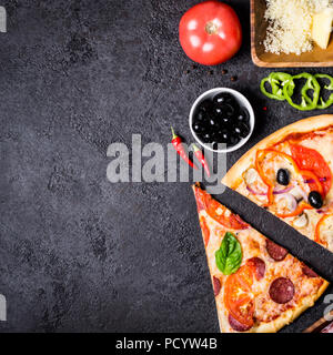 Selezione di pezzi assortiti pizza su sfondo nero e gli ingredienti. Salsiccia per pizza vegetariana e frutti di mare Pizza. Foto Stock
