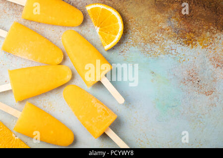 Popsicles arancione con il succo su un bacground blu. Ice pops, piatto di laici che, vista dall'alto con copia spazio. Foto Stock