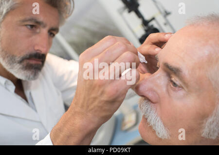All'ottico optometrista utilizzando midriatici collirio per intorpidire gli occhi Foto Stock