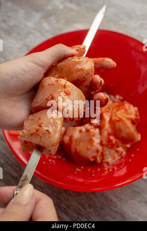 Mani femminili infilza carne marinaded paci su spit Foto Stock