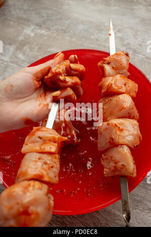 Mani femminili infilza carne marinaded paci su spit Foto Stock