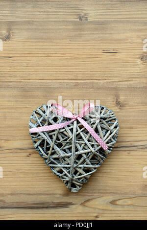 Un cuore di paglia su un sfondo di legno Foto Stock
