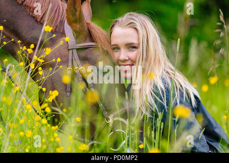 Donna sorridente seduto nel prato con il suo cavallo arabo Foto Stock