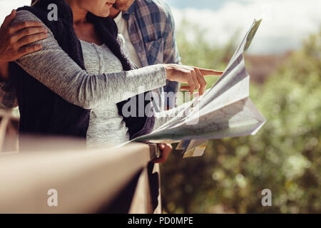 Donna puntando verso la mappa permanente, mentre con il suo fidanzato. Coppia in cerca di destinazione di viaggio sulla mappa. Foto Stock
