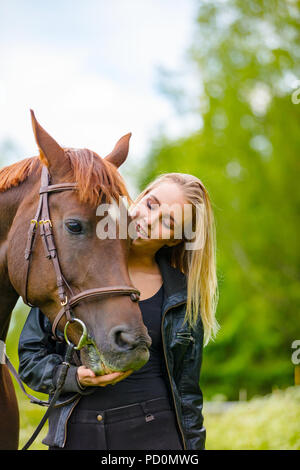 Giovane donna con il suo cavallo arabo in piedi nel campo Foto Stock