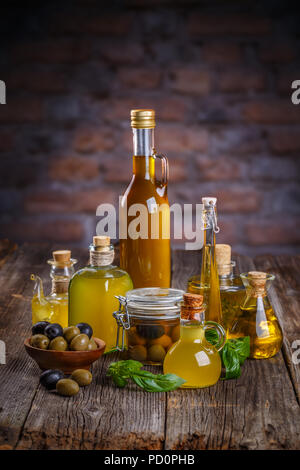 Ancora in vita di olive nere e verdi in ciotole di legno e olio pressato in bottiglie di vetro Foto Stock