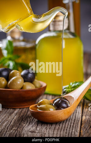 Olio di oliva riversando olive nere e verdi Foto Stock