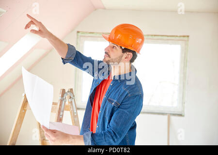 Colpo di giovane ingegnere portatile tenuta in mano e mostrando qualcosa di permanente, mentre al sito in costruzione. Foto Stock