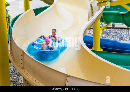 PHUKET, Tailandia - 8 luglio 2017 - asiatici mamma e figlia e far scorrere verso il basso il cursore di acqua sul doppio galleggiante alla giungla Splash Water Park a Phuket, Tailandia sul J Foto Stock