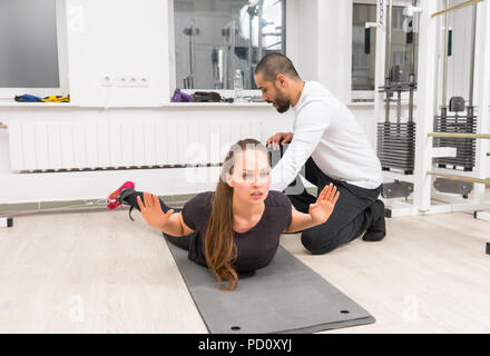 Personal trainer ad aiutare la donna a esercitare sul cavo crossover macchina Foto Stock