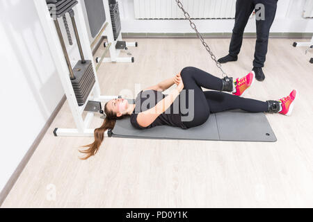 Donna che esercitano le gambe sul cavo crossover macchina alla palestra Foto Stock