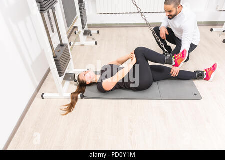 Donna che esercitano sul cavo crossover macchina con personal trainer alla Palestra Foto Stock