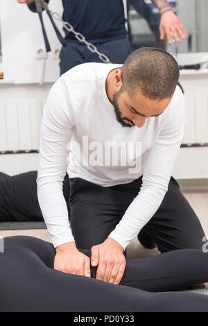 Bel giovane maschio nero massaggiatore donna di massaggio per le gambe in palestra Foto Stock