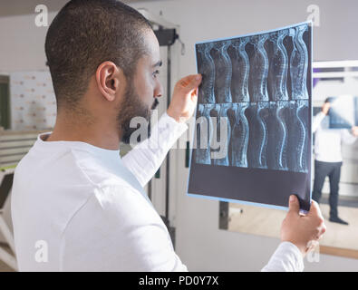 Close Up dei maschi di fisioterapista o chiropratico o medico guardando film a raggi X della colonna vertebrale nella parte anteriore della scatola luminosa in clinica Foto Stock