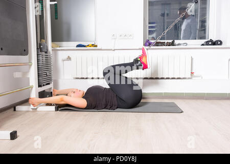 Giovane donna che esercitano le gambe con il peso sul cavo crossover macchina alla palestra Foto Stock