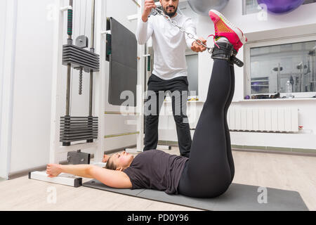 Donna che esercitano sul cavo crossover macchina con personal trainer alla Palestra Foto Stock