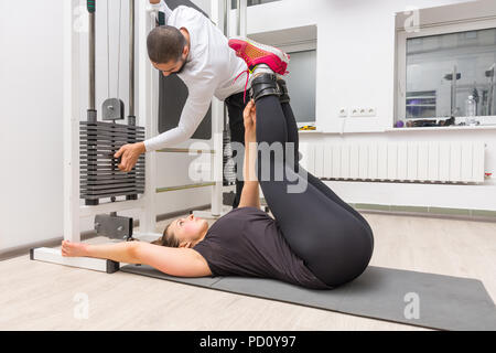 Donna che esercitano sul cavo crossover macchina con trainer alla Palestra Foto Stock