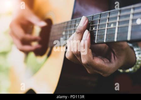 Stretta di mano il chitarrista suonando la chitarra. Musical e concetto di strumento. All'aperto e a tema libero. Il fuoco selettivo sulla sinistra. Foto Stock