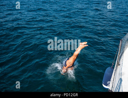 Trieste, Italia, il 4 agosto 2018. Un uomo che si tuffa in acqua da una barca a vela nel mare Adriatico, vicino a Trieste. Foto di Enrique Shore Foto Stock