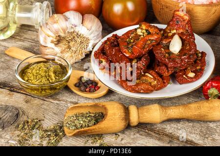 Pomodori secchi sott'olio in olio di oliva con aglio. Semi di girasole con pomodori su un vecchio tavolo in legno Foto Stock