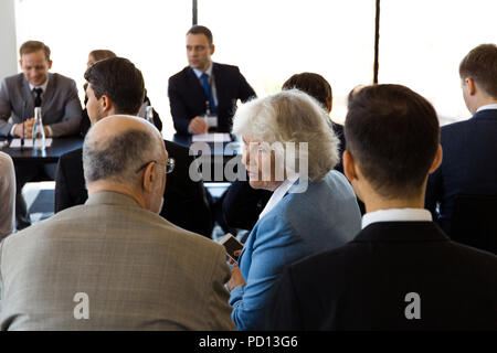 Pubblico di uomini di affari che seduta alla camera di formazione e parlare, altoparlanti sittingat la tabella con i documenti, microfoni e acqua Foto Stock