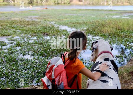 Una giovane ragazza in bianco e nero un alano cane insieme che si affaccia su un fiume, Booroona sentiero a piedi sul fiume Ross, Rasmussen QLD 4815, Australia Foto Stock