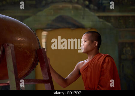 Un giovane monaco buddista giocando un tamburo durante una cerimonia in un monastero a Siem Reap, Cambogia. Foto Stock