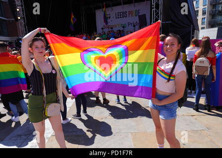 2 ragazze posano con un flag di LGBT durante il Leeds LGBT Pride evento al Millennium Square nel centro cittadino di Leeds Foto Stock