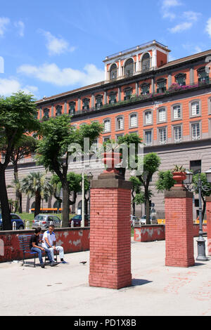 Due uomini seduti su una panchina di fronte al Palazzo Reale di Napoli (lato posteriore del palazzo), Napoli, Italia Foto Stock