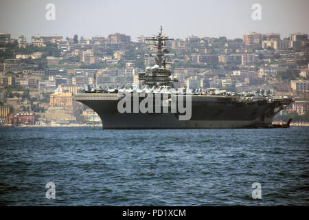 La USS George H. W. Bush ancorata di fronte al bellissimo paesaggio di Napoli, Italia, con abbondanza di F-18s visibile sul ponte del vettore Foto Stock