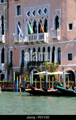 Cinque gondole nero sono ormeggiati per le strisce di pile nella parte anteriore di un hotel tradizionale con facciata di colore rosa Foto Stock