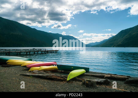 Il lago di Crescent con fila di kayak sdraiato sulla spiaggia e al molo in un giorno nuvoloso, il Parco Nazionale di Olympic, nello stato di Washington, USA. Foto Stock