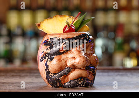 La Pina Colada su sfondo di legno guarnita di ananas e ciliegia ceramick in vetro in forma di pirata dei Caraibi Foto Stock