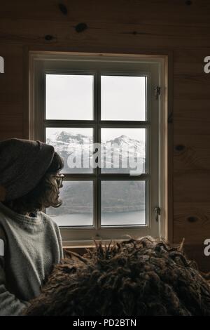 Donna che guarda fuori dalla finestra per la neve Foto Stock