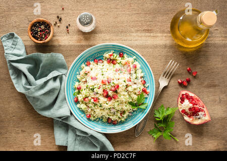 Arabo vegetariano Insalata di couscous tabulé con i semi di melograno, prezzemolo e olio di oliva. Vista superiore Foto Stock