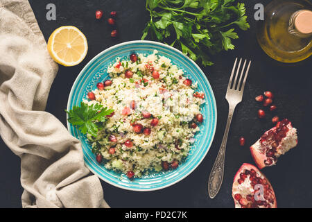 Medio Oriente tabulé insalata con cuscus, i semi di melograno, prezzemolo. Vista superiore, tonica immagine Foto Stock