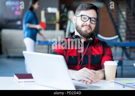 Sorridente uomo barbuto in ufficio IT Foto Stock