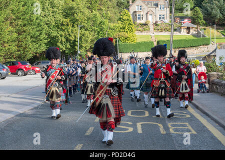 A Aberlour, Scozia - 06 August, 2018: bande di cornamuse marciando attraverso il villaggio dopo i Giochi delle Highland a Aberlour, Scozia. Foto Stock