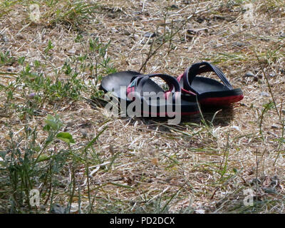 Una coppia di uomini flip flop vicino a terra vicino al bordo delle acque Foto Stock