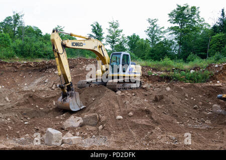 Un Kobelco SK 250 LC escavatore idraulico parcheggiato in una spiaggia di sabbia e ghiaia pit nelle Montagne Adirondack, NY USA Foto Stock