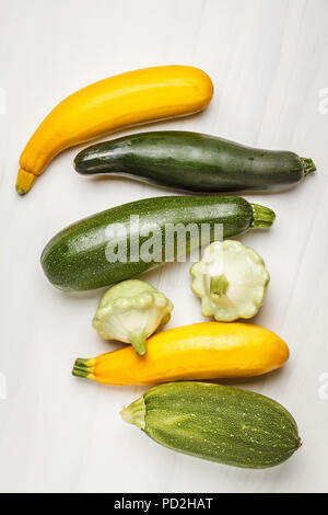 Diversi tipi di zucchine su sfondo bianco, vista dall'alto. Pulire sano concetto di mangiare. Foto Stock