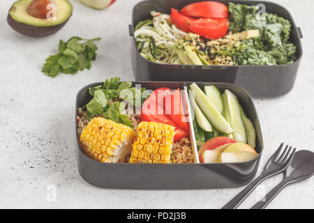 Pasto sano prep contenitori con la quinoa, avocado, mais, zucchine tagliatelle e Kale. Cibo da asporto. Sfondo bianco, vista dall'alto. Foto Stock