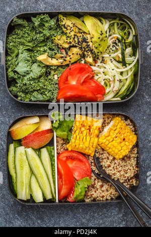 Pasto sano prep contenitori con la quinoa, avocado, mais, zucchine tagliatelle e Kale. Cibo da asporto. Sfondo scuro, vista dall'alto. Foto Stock