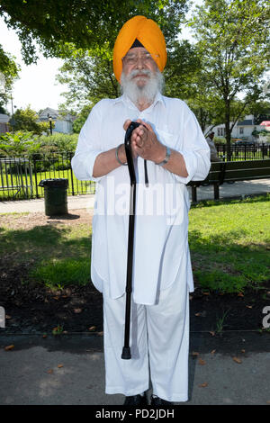 Un illustre uomo Sikh in tradizionali vestiti di bianco in un esterno di preghiera sessione in Smokey Park, Richmond Hill, Queens, a New York Foto Stock