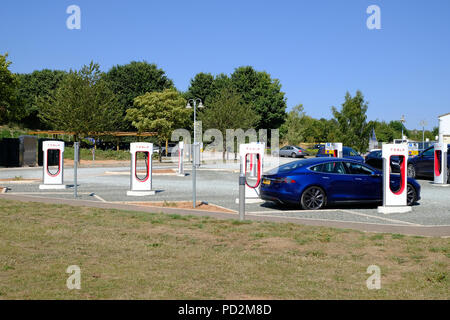 Topsham, Devon, Regno Unito. Tesla Model S la carica a un sovralimentatore di Tesla dalla stazione di freccette Farm Foto Stock
