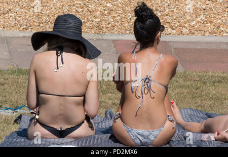 Giovani donne che indossano bikini seduta nel sole caldo a prendere il sole durante la canicola. Foto Stock