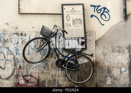 Bici nera con cesto, parcheggiata appesa su un cartello turistico. Centro di Roma, Italia, Europa, Unione europea, UE. Foto Stock