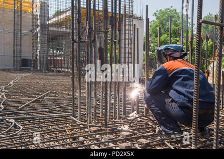 Operaio edile di metallo di saldatura rebar per la colata di fondazione. candide, persone reali Foto Stock